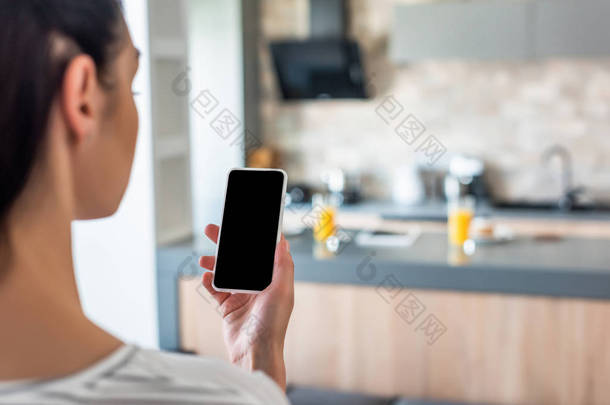 厨房手持手机空白屏幕的女性选择焦点