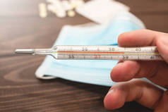 一个医疗用的汞温度计，手头上显示了39摄氏度的高温。木制背景。保健、医疗和疾病预防主题.