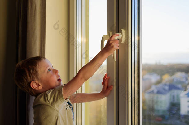 没有父母的孩子打开窗户，拿着把手。危险局势