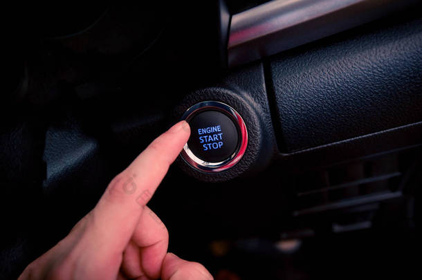 在现代汽车技术中, 按下启动汽车/按钮推式发动机启动停止-我的汽车上的手手指按下按钮