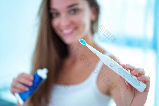 快乐<strong>健康</strong>的微笑的女人在浴室里用超声波电刷在家里。<strong>口腔</strong>卫生和牙齿护理