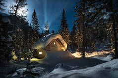 在夜晚月亮的美丽的雪森林的小屋