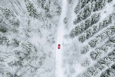 冬季道路和红色轿车覆盖着积雪森林的空中俯瞰.