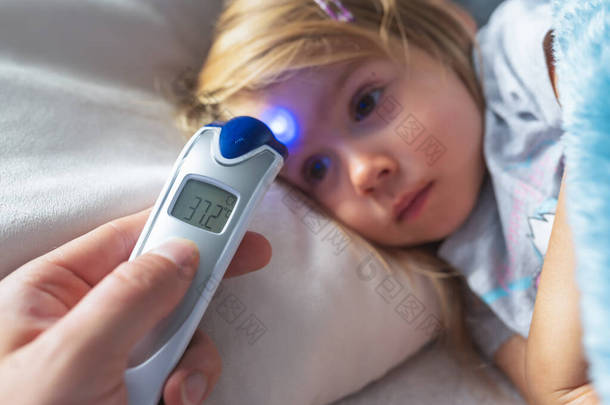 母亲在家里用红外温度计为孩子<strong>量体温</strong>，她的手拿着数字式红外温度计.