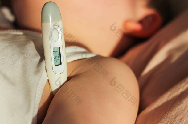儿童温度测量的闭锁。一个体温正常的孩子正在康复.场深度小，以温度计为重点