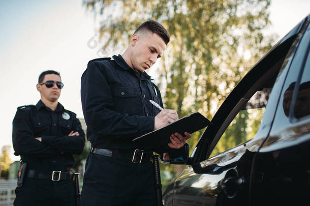 男警官在路上用制服检查车辆。法律保护, 汽车交通检查员, 安全控制工作
