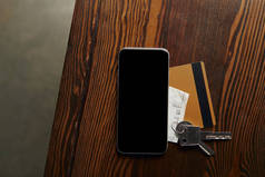 木桌上信用卡、智能手机、支票和钥匙的顶部视图