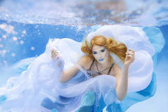 水下时尚的美丽金发的年轻女子，穿着蓝色衣服的肖像