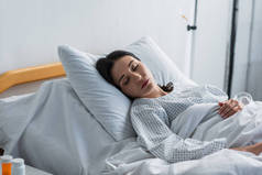 身穿病人长袍的黑发女人躺在病床上