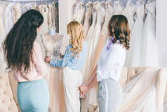 快乐的新娘和伴娘试穿礼服在婚礼画室