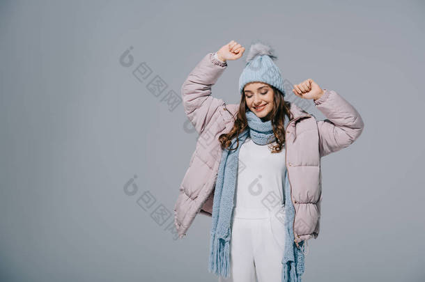 穿着<strong>保暖</strong>外套、头戴针织帽子、戴着围巾、与灰色隔绝的迷人的快乐女人
