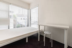 公寓小卧室里的单人床和白桌