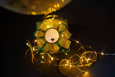 绿色的礼物，金色的弓，饰有闪亮的彩灯，心胸狭窄，背景漆黑，圣诞光彩夺目。节假日节假日。复制空间。照片：