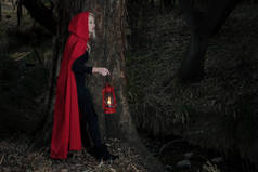 迷人的女人头戴小红帽，头戴灯笼，走在一片漆黑的森林里