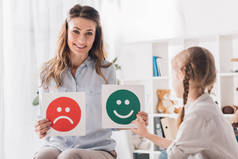 微笑心理学家显示快乐和悲伤的情感面孔卡片给孩子