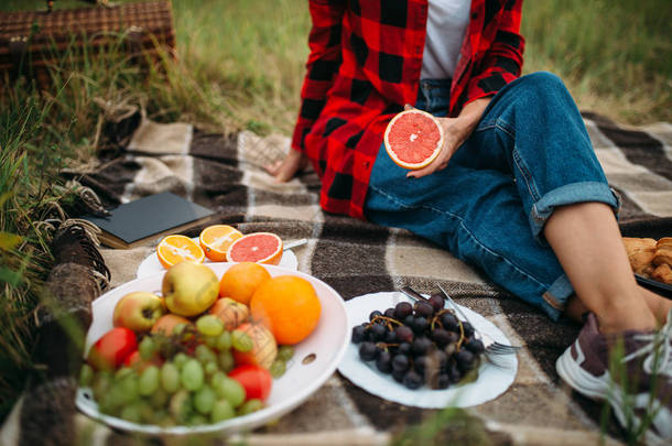 女人带着水果坐在格子上, 在<strong>夏日</strong>野餐。浪漫的<strong>旅游</strong>, 快乐的假期