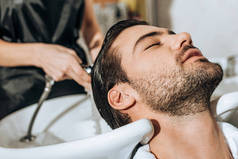 特写部分的发型师洗头英俊的年轻男性客户在美容院