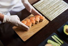 滚动寿司制作过程的特写视图。主厨在木板上供应新鲜可口的面包卷