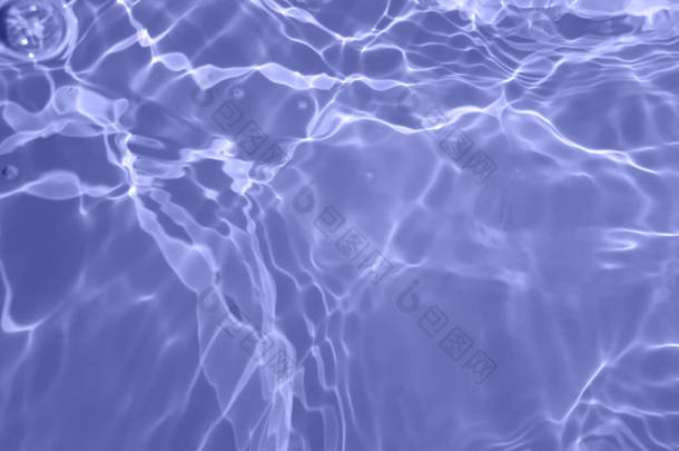 Defocus模糊了透明的蓝色清晰平静的水面纹理与水花和气泡。潮流抽象的自然背景.阳光下的水波有复制空间.蓝色水彩斑斓
