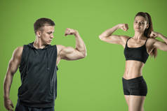 一个年轻的肌肉发达的女人和一个健康的男人站在绿色的背景.