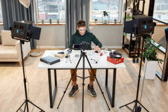 年轻男性科技博主在家庭工作室录制有关新智能手机的视频博客或博客的全长照片。Blog, Work from Home concept