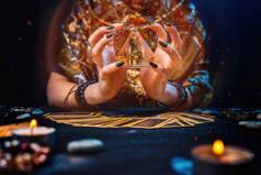 巫术。巫婆手里拿着一个发光的金字塔,变魔术了.塔罗牌在桌子上。手举得很近占卜和占星术的概念.