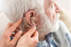 妇女帮助白发男子, 戴着助听器的景象