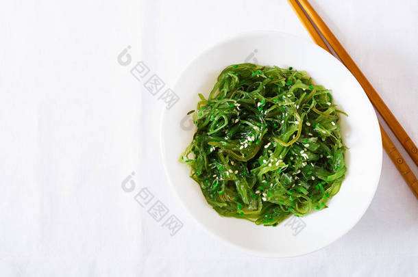 裙带菜 Chuka 或海藻沙拉与芝麻种子在碗中的白色背景。传统的日本料理。顶部视图。平躺