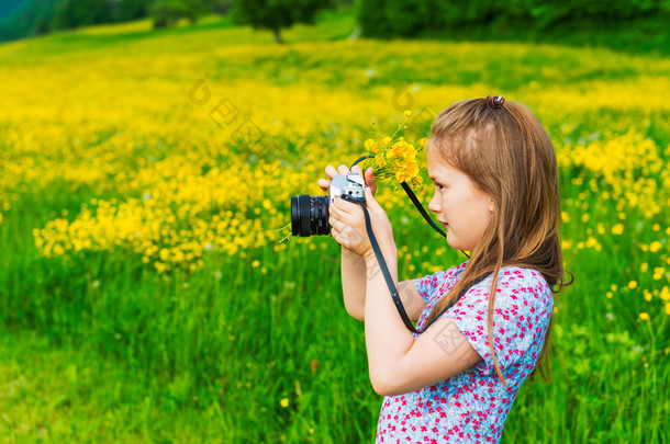 可爱的小女孩拍照的<strong>性质</strong>，拿着相机和束黄色毛茛
