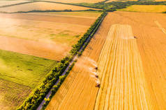 收获小麦。日落时，四个红色联合收割机在田里干活。空中无人驾驶飞机照片