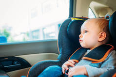 可爱的小婴儿坐在儿童安全座椅汽车和看通过窗口