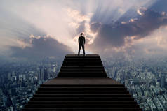 成功和领导者的概念, 商人在适合站在楼梯上, 用阳光俯瞰城市