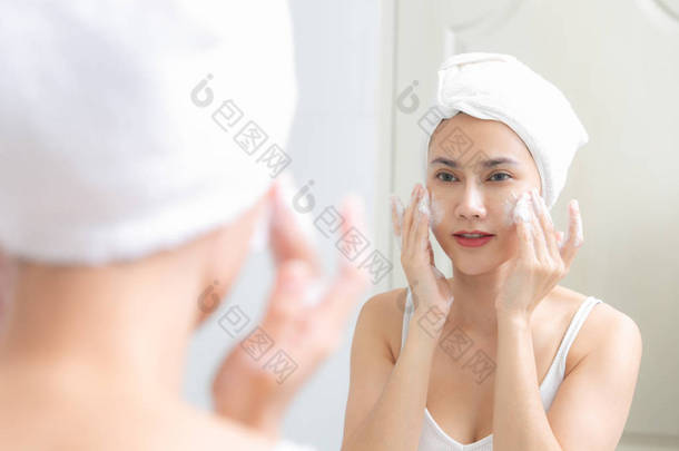 亚洲女人用泡沫清洁面部肌肤让自己快乐.