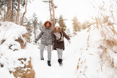 一对年轻的夫妇, 一个男人和一个女人在冰雪覆盖的森林里散步。冬季休闲。一起旅行。爱会在任何霜冻中温暖