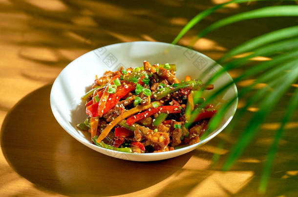 牛肉在甜酸的酱汁中打滚,蔬菜和四川胡椒放在一个碗里.中国菜