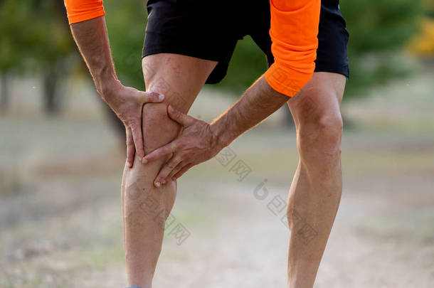 在户外公园的跑步锻炼中, 年轻的健康男子在运动训练中的一次跑步锻炼中, 手牵着膝盖, 在肌肉受伤、骨折、骨折、疼痛或抽筋的情况下.