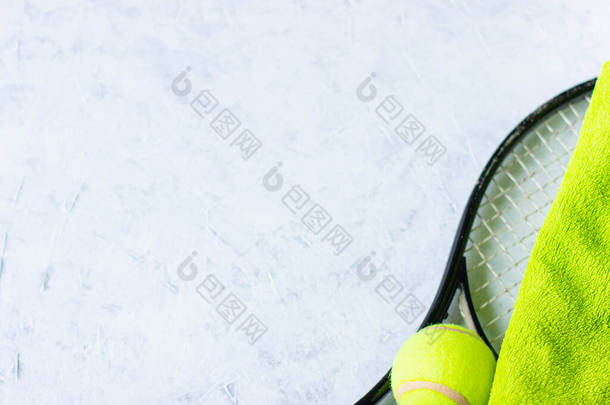 网球拍、球和绿色毛巾躺在轻薄的背景上，高瞻远瞩，体育简约主义