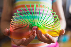 在彩色条纹T恤的背景下，儿童手中的细长玩具的特写- -对玩具的选择性关注