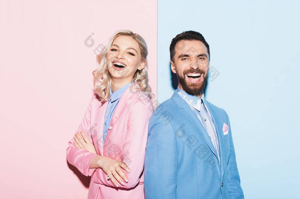 迷人的女人和英俊的男人在粉色和蓝色背景的相机前微笑