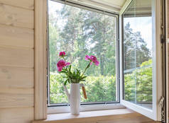 白色的窗户,有蚊帐,在一座俯瞰花园的乡村木屋里.浇灌的粉红色牡丹花束可以放在窗台上