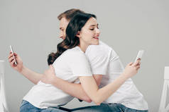 年轻男女在使用灰色智能手机时拥抱在一起