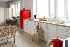 轻便的现代化厨房的内部，有红色冰箱、白色柜台和扶手椅