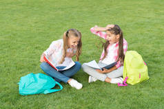 从笑话中大笑。在绿草上玩得开心。两个背着背包的小孩。小女孩在课间休息时玩耍和学习。孩子们快乐的一天。姐妹关系和家庭观念。知识的日子来了