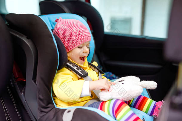 可爱的女婴与蓝眼睛和五颜六色的衣服坐在<strong>汽车</strong>座椅上。幼儿穿着冬衣去家庭度假和乔尼。<strong>安全</strong>旅行、儿童<strong>安全</strong>、交通