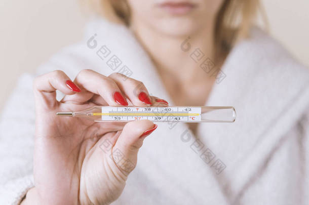 手握温度计的妇女，在感染流感时测<strong>量体温</strong>.