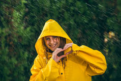 穿黄色雨衣的女孩在雨中玩得开心
