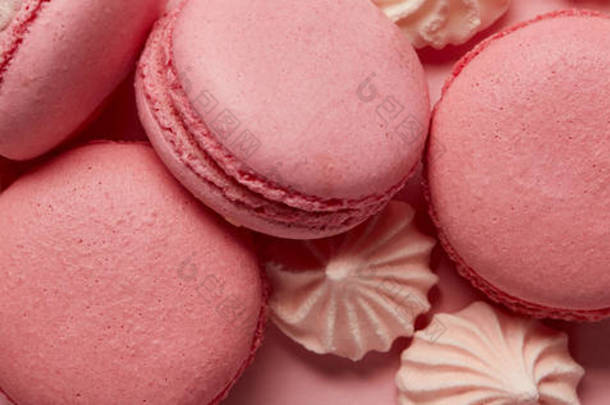 美味的各种马卡龙与粉红色的小粉红色和白色梅林格在粉红色背景