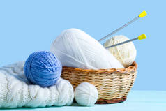 白色和蓝色针织纱球, 针织针织和蓝色背景上的白色针织毛衣。针织概念。针织和冬衣