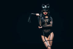 性感的年轻黑发女人在bdsm服装和面具与皮革鞭打鞭孤立在黑色