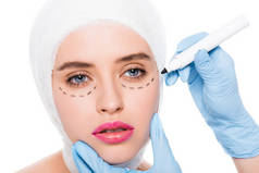 裁剪的意见整形外科医生在乳胶手套拿着标记笔靠近妇女与标记在脸上查出在白色